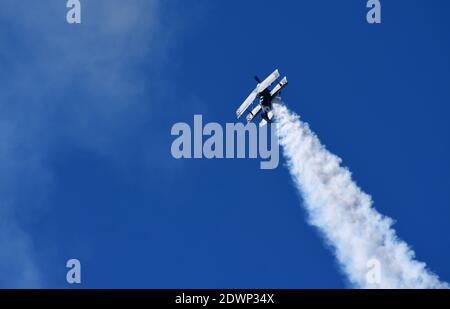 Pitts modèle 12 stunt byplane avec sentier de fumée et ciel bleu. Banque D'Images