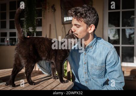 le chat noir s'approche d'un jeune homme avec des expositions d'affection. mouvement 1 Banque D'Images