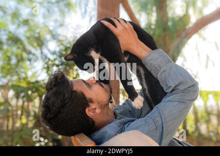 le jeune homme et le chat noir se regardent les uns les autres. gros plan Banque D'Images