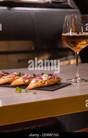 Un clos de savoureuses tapas à l'oignon, au thon, au pain et à la mayonnaise, servi avec un verre de vin blanc Banque D'Images