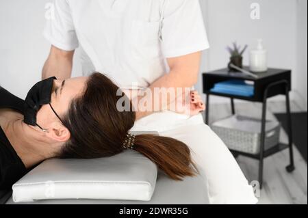 Thérapeute masculin donnant un massage pour soulager la douleur d'épaule à une patiente dans la clinique de physiothérapie. Photo de haute qualité. Banque D'Images