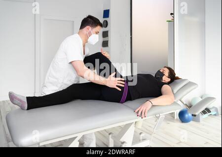 Femme allongé sur la table de massage tandis que son thérapeute physique faisant des exercices spéciaux pour la thérapie physique pour la sciatique et les problèmes de nerf pincé. Photo de haute qualité Banque D'Images