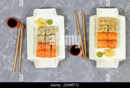 Sélection de sushis variés dans le plateau d'emballage en papier écologique blanc vue de dessus de fond en pierre grise Banque D'Images