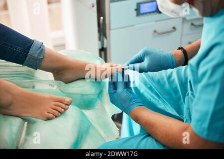 Belle femme visitant podiatre et recevant un traitement professionnel sur le jambes dans le centre médical Banque D'Images