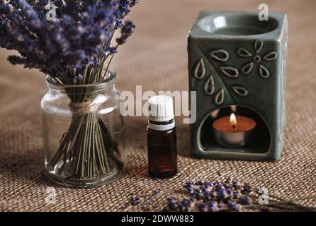 Lampe d'arôme avec une huile aromatique et une bougie brûlante avec un seau de lavande dans le verre, concept d'aromathérapie Banque D'Images