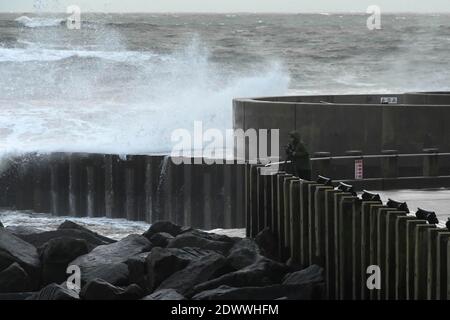 West Bay, Dorset, Royaume-Uni. 23 décembre 2020. Météo Royaume-Uni. Un photographe qui prend des photos des mers orageux alors qu'elles s'écrasont contre les défenses de la mer à West Bay à Dorset lors d'un après-midi de pluie et de vents violents. Crédit photo : Graham Hunt/Alamy Live News Banque D'Images