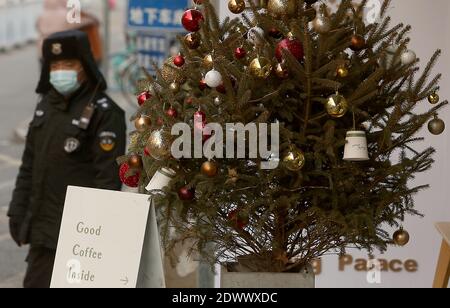 Pékin, Chine. 23 décembre 2020. Un policier surveille la circulation à côté d'un arbre de Noël placé à l'extérieur d'un café occidental à Beijing le mercredi 23 décembre 2020. Noël est devenu un événement majeur en Chine avec l'accent étant mis sur le shopping et les dîners avec la famille et les amis. Photo de Stephen Shaver/UPI crédit: UPI/Alay Live News Banque D'Images