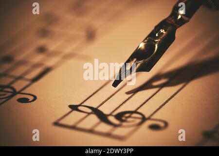 écrire des notes musicales sur une feuille avec un stylo et de l'encre. éducation musicale. gros plan Banque D'Images
