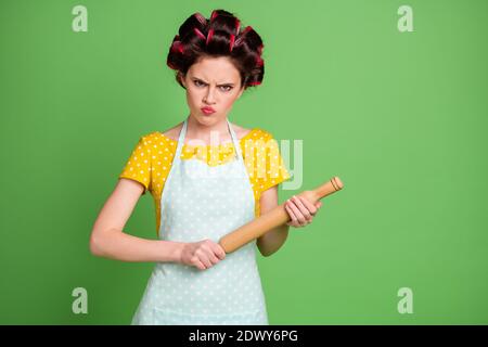 Photo de joli fâché jeune fille rouleau cheveux menaçant look tenir la goupille à roulettes prête punir le mari appelé déjeuner pas bon portez une chemise à pois Banque D'Images