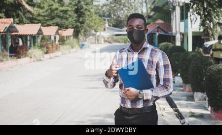 Portrait d'un professeur africain dans un masque de visage debout à l'extérieur école Banque D'Images