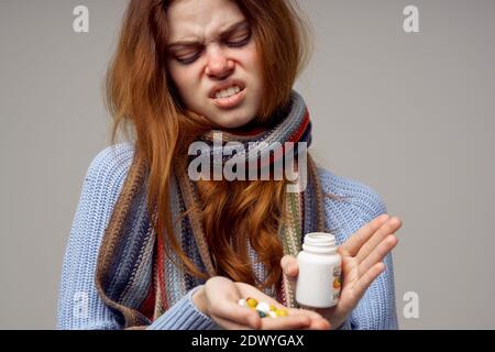 femme malade avec des pilules dans ses mains vitamines fond gris écharpe chaude Banque D'Images