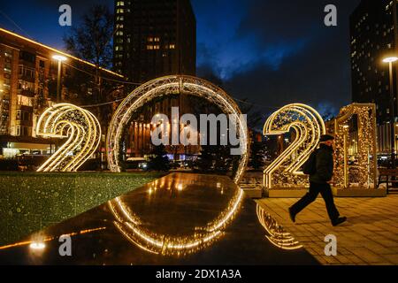 Moscou, Russie. 23 décembre 2020. Un homme passe devant des décorations lumineuses pour le nouvel an à Moscou, en Russie, le 23 décembre 2020. Credit: Evgeny Sinitsyn/Xinhua/Alay Live News Banque D'Images