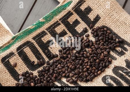 Les grains de café rôtis foncés reposent sur un sac de jute standard Texte de marquage noir café Banque D'Images