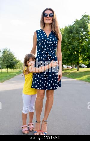 Une mère marche avec sa fille en été dans le parc de la ville. Petite fille de 5-7 ans, épouse sa mumu, sourires heureux se réjouit et repose sur le week-end pour un Banque D'Images