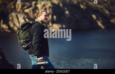 Un voyageur heureux se tenant au sommet d'une falaise et admirant la beauté de la nature. Un fond de lac. Voyage, aventure, nature, concept de liberté.A Banque D'Images