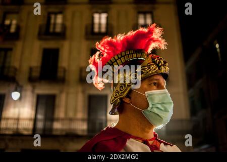 Un homme vêtu d'un costume biblique représentant un centurion romain porte un masque protecteur lors d'une scène de Nativité en direct exécutée dans le centre de Barcelone. Banque D'Images