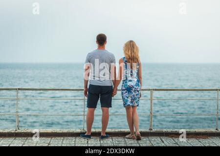 Jeune couple debout sur la rive tenant les mains et appréciant vue sur la mer Banque D'Images