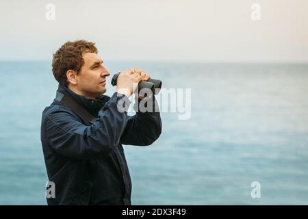 Homme caucasien sur le fond de la mer préparé à regardez à travers les jumelles Banque D'Images