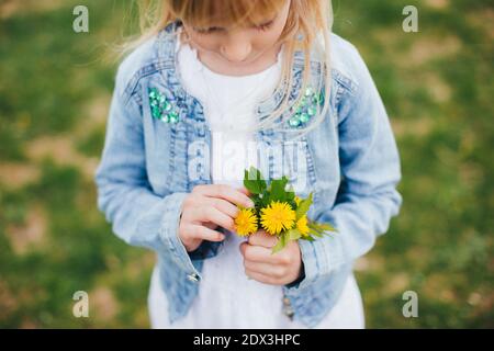 Une petite fille tient un bouquet de fleurs jaunes Banque D'Images