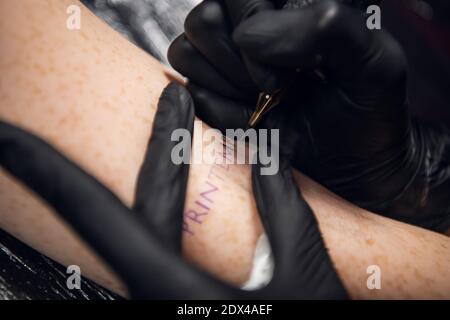 Gros plan bâton et méthode de poke pour tatouer la main d'une jeune fille avec l'inscription dans le Printemps français -- printemps Banque D'Images
