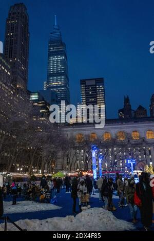 Les gens qui apprécient les arbres de Noël illuminés dans le village de vacances de Bryant Park lors d'une soirée hivernale, New York City, États-Unis Banque D'Images