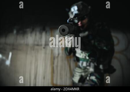 Un soldat des États-Unis à part entière, MARSOC, armé d'un fusil d'assaut, traverse le bâtiment abandonné. Affrontement militaire. Banque D'Images