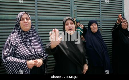 Les parents de membres palestiniens de la famille Tayseer Al-Batsh, qui, selon les autorités de l'hôpital, ont été tués lors d'une attaque aérienne israélienne, pleurent lors de leurs funérailles à Gaza le 13 juillet 2014. L'attaque aérienne israélienne sur le domicile familial d'Al-Batsh, le chef de police de Gaza, a tué 18 personnes samedi, a déclaré le ministère de la Santé de Gaza, et le Hamas a tiré le plus grand salvo de roquettes encore sur tel Aviv depuis le début de l'offensive de l'État juif dans l'enclave palestinienne. L'attaque sur le domicile d'Al-Batsh dans la ville de Gaza a été l'attentat le plus meurtrier depuis le lancement par Israël de son offensive mardi pour mettre fin à la fusée palestinienne Banque D'Images