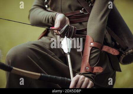 Gros plan. Flèches et arc dans les mains des femmes. Tir à l'arc en costume médiéval. Banque D'Images