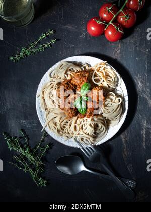 Spaghetti aux boulettes de viande rôties dans une sauce tomate. Cuisine italienne traditionnelle. Prise de vue en hauteur avec espace de copie. Sombre et moody. Banque D'Images