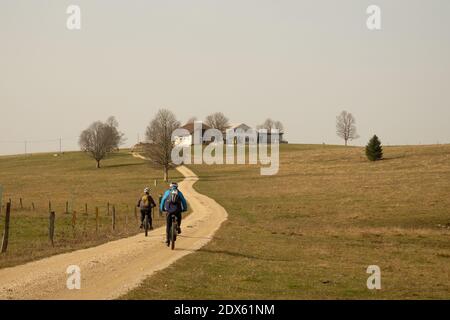 Deux VTT sur une route de gravier en face de Une ferme dans les collines du Jura suisse Banque D'Images