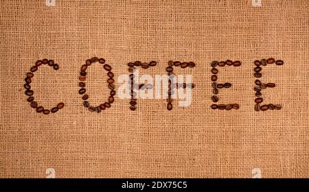 Grains de café torréfiés disposés en lettres café sur sac en toile. Banque D'Images