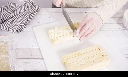 Étape par étape. Coupe de fudge de canne à sucre fait maison sur un tableau de découpe blanc. Banque D'Images