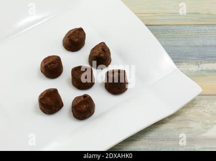 Les truffes au chocolat au cacao saupoudrées sont à déguster sur une assiette de dessert blanche tableau Banque D'Images