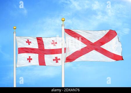 Géorgie et Irlande du Nord deux drapeaux sur les mâts de drapeaux et le bleu ciel Banque D'Images