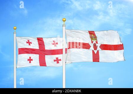 Géorgie et Irlande du Nord deux drapeaux sur les mâts de drapeaux et le bleu ciel Banque D'Images