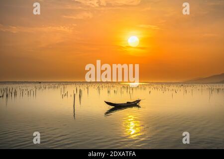 Bateau de pêche dans le grand lagon au coucher du soleil. C'est le principal moyen de transport pour pêcher des poissons dans le centre du Vietnam Banque D'Images