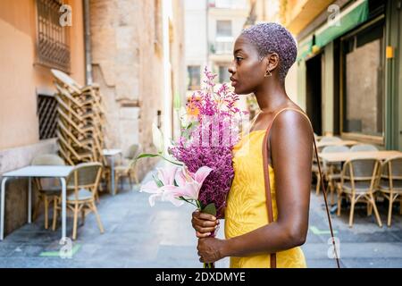 Culotte taille basse femme confiante avec bouquet de fleurs en ville Banque D'Images