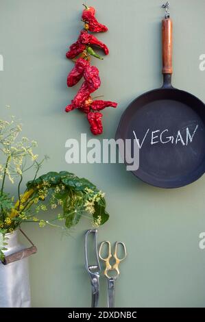 Décoration rustique de cuisine avec poêle en fonte, Chili séché, verger suisse, fleur de fenouil, pot à lait rétro, ciseaux vintage Banque D'Images