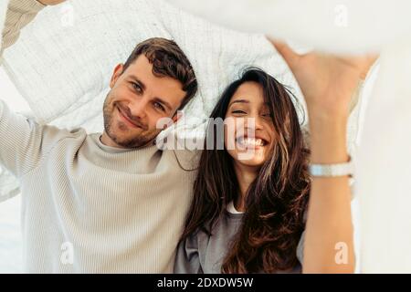 Jeune couple souriant en se tenant sous le châle Banque D'Images
