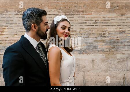 Heureux couple marié debout près du mur Banque D'Images
