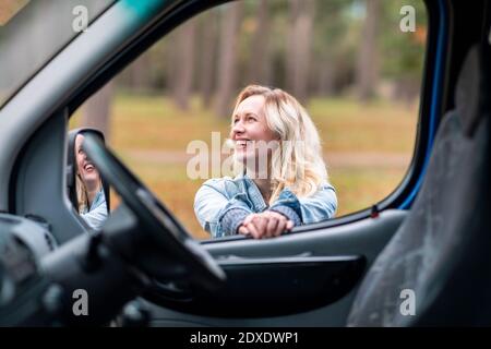 Femme gaie vue depuis la fenêtre de la camionnette de camping Banque D'Images