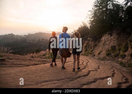 Amis avec sac marchant ensemble sur le sentier de montagne pendant le coucher du soleil Banque D'Images