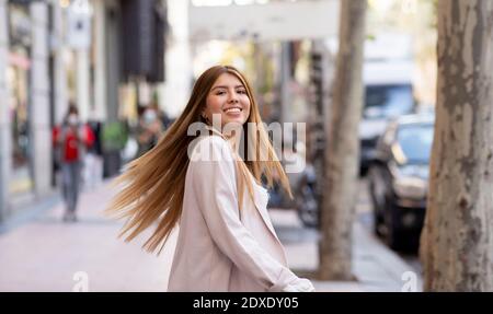 Femme souriante qui tourne sur la piste de la ville Banque D'Images