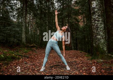 Jeune sportswoman s'étirant en forêt Banque D'Images