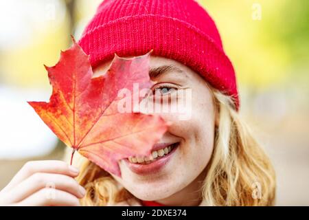 Adolescente portant un chapeau couvrant le visage avec des feuilles à l'extérieur Banque D'Images