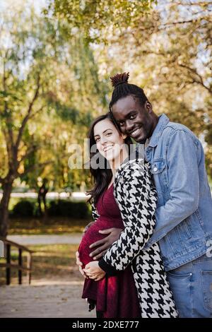 Bonne femme enceinte debout avec un homme dans le parc Banque D'Images