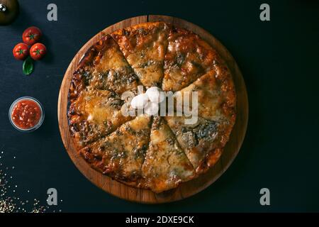 Vue de dessus traditionnelle croustillante pizza italienne à quatre fromages sur un fond rustique en bois noir. Vue de dessus de pizza chaude. Banque D'Images