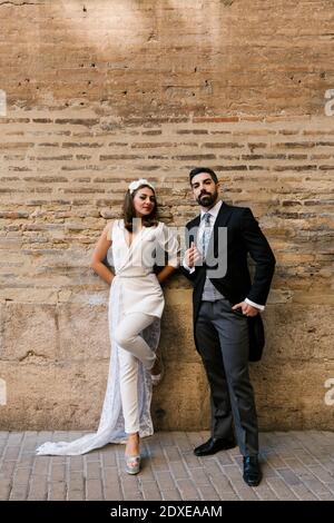 Jeune couple nouvellement marié debout contre le mur sur la piste de marche Banque D'Images