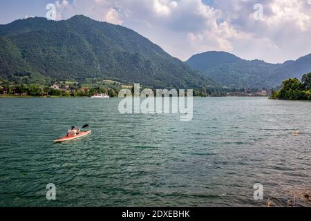 Homme expérimenté actif faisant du kayak sur le lac Idro contre un ciel nuageux Banque D'Images