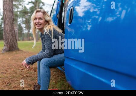 Femme souriante assise à la porte de la camionnette de camping à Cannock Poursuite Banque D'Images